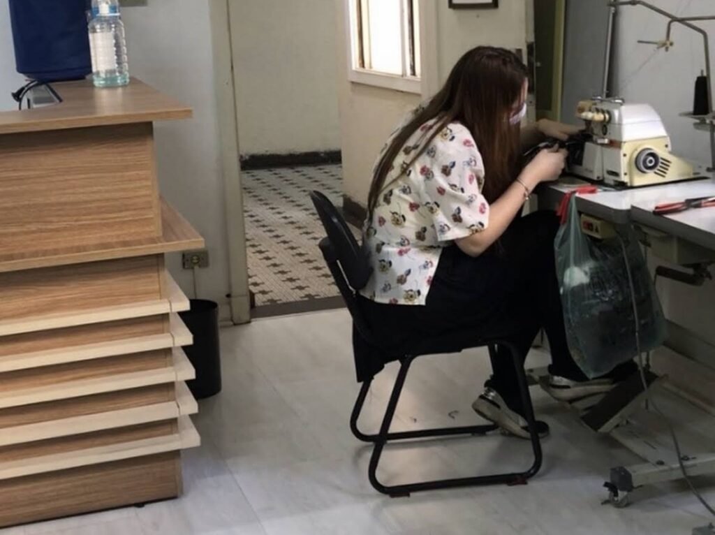 Aluna do curso de costura infantil costurando peça na máquina overloque