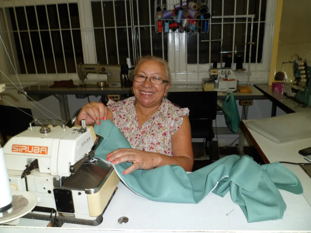 Aluna do curso de corte e costura da Escola de Moda Paulistana em São Paulo costurando na máquina overloque durante aula prática