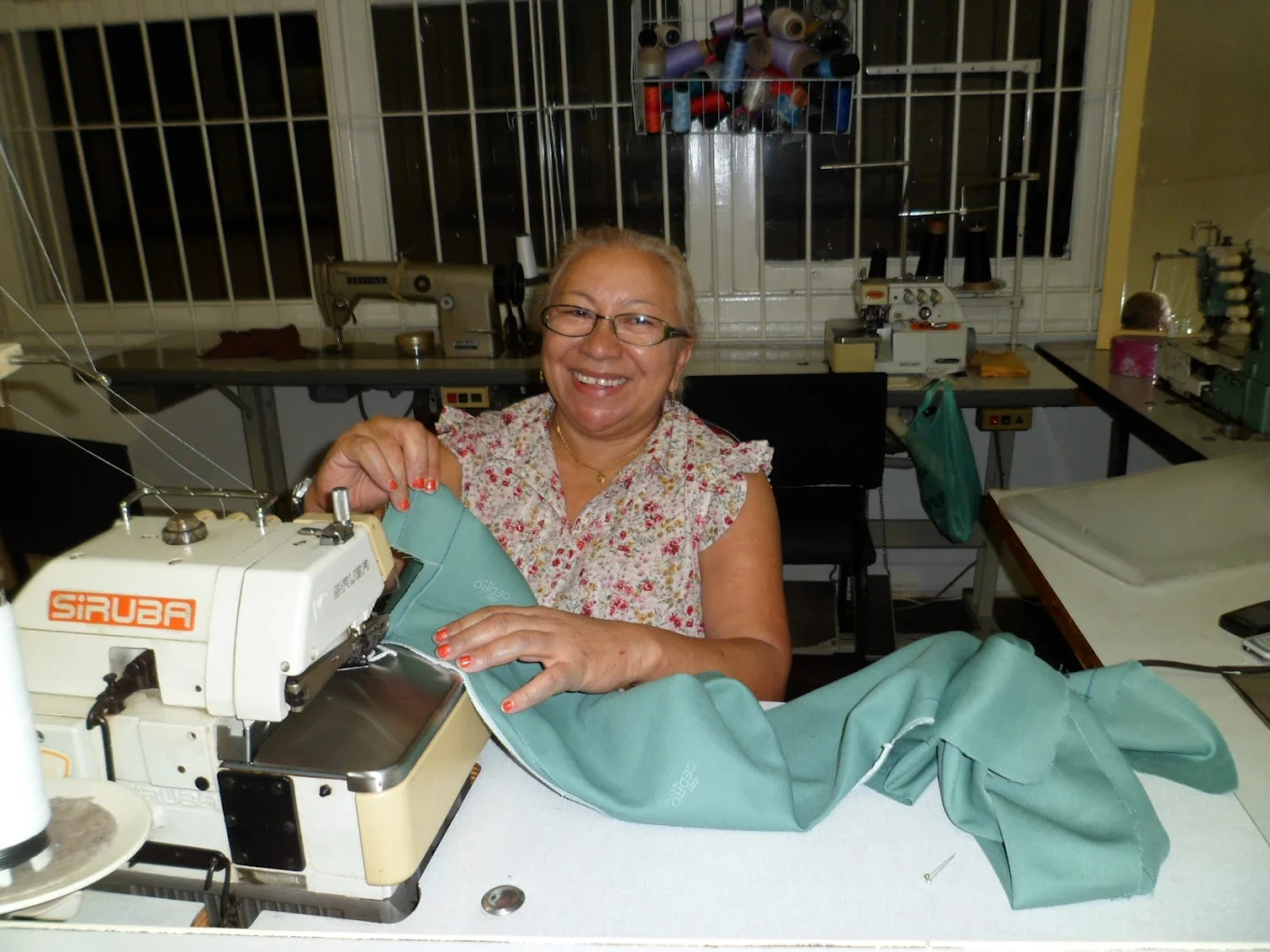 Aluna do curso de corte e costura da Escola de Moda Paulistana utilizando máquina overloque durante aula prática em São Paulo