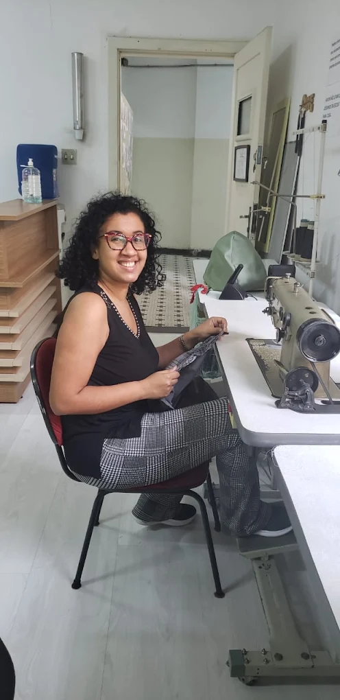 Aluna do curso de corte e costura da Escola de Moda Paulistana utilizando máquina reta em aula prática em São Paulo