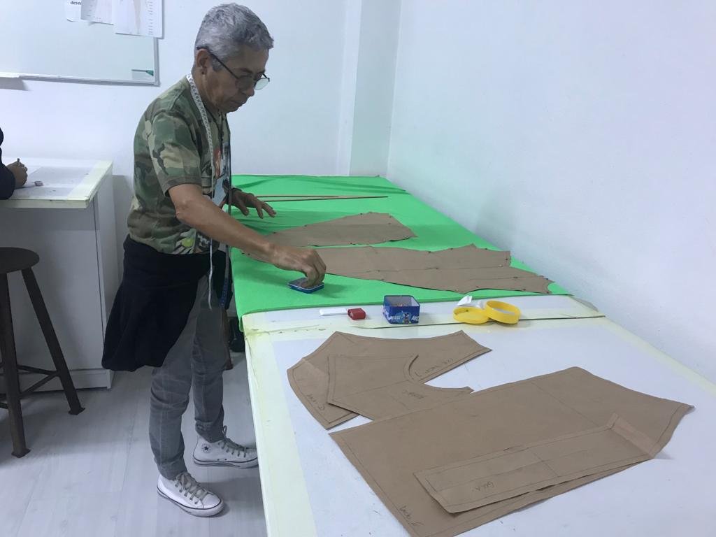 Niko Rosa, figurinista e aluno da Escola de Moda Paulistana em São Paulo, ajustando o enfesto de tecido com molde durante aula prática do Método Berimod.